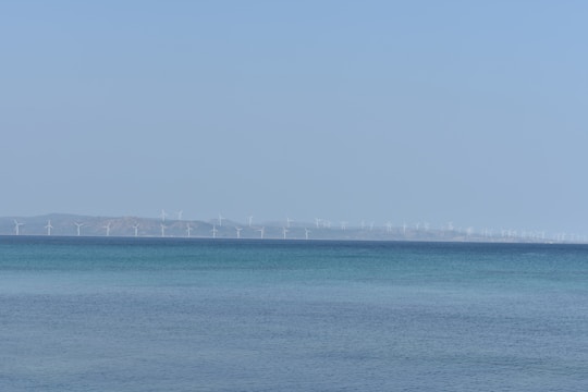 A panoramic view of offshore wind turbines stretching across the sea under a clear sky.