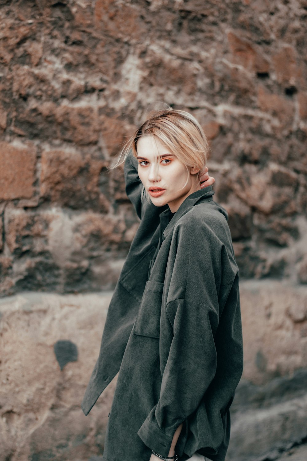 woman in black hoodie standing near brown wall