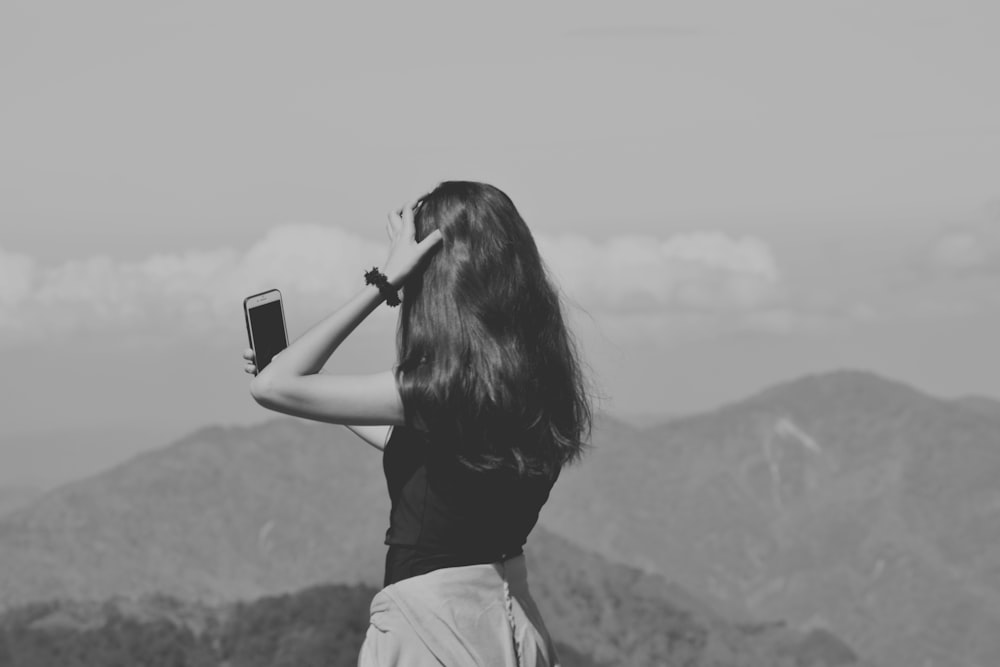 woman in black shirt taking photo of mountain