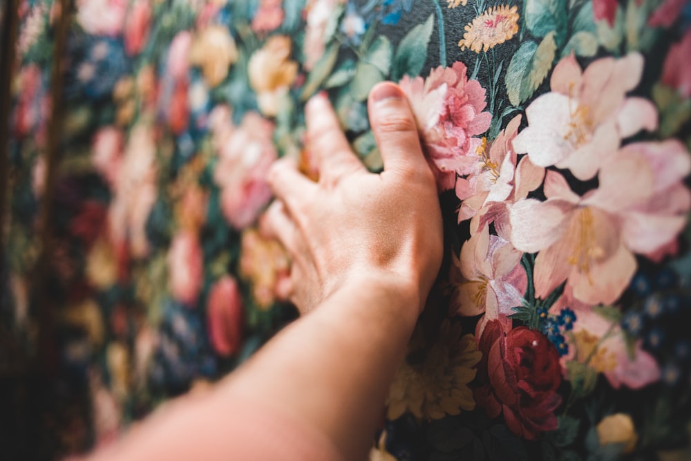 persons hand on floral textile