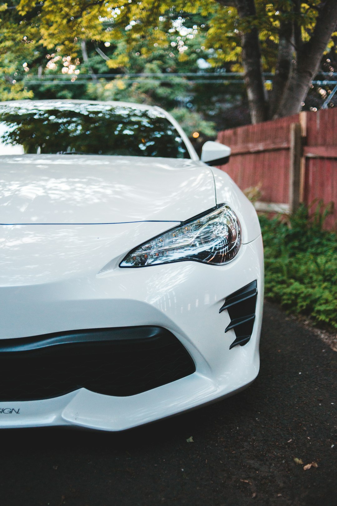 white and blue car near brown wooden fence during daytime