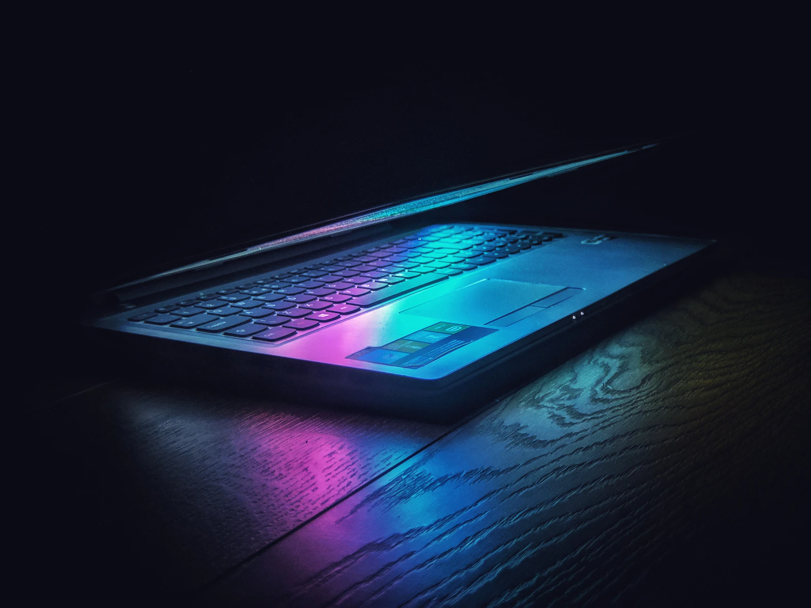 Laptop z kolorowym światłem odbitym na klawiaturze