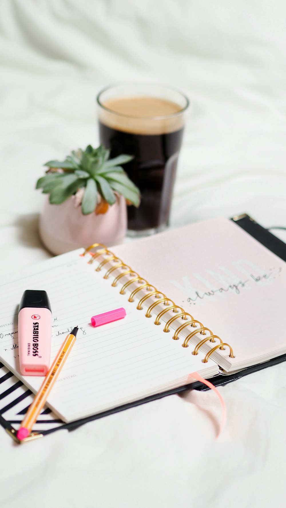 white notebook beside black pen