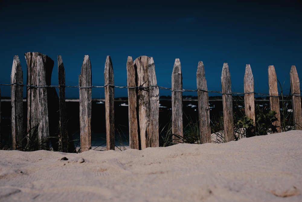 clôture en bois marron sur sable brun sous ciel bleu pendant la journée