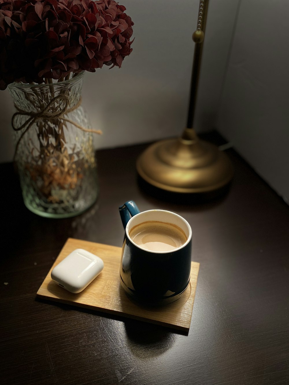 white ceramic mug on black saucer beside red flowers