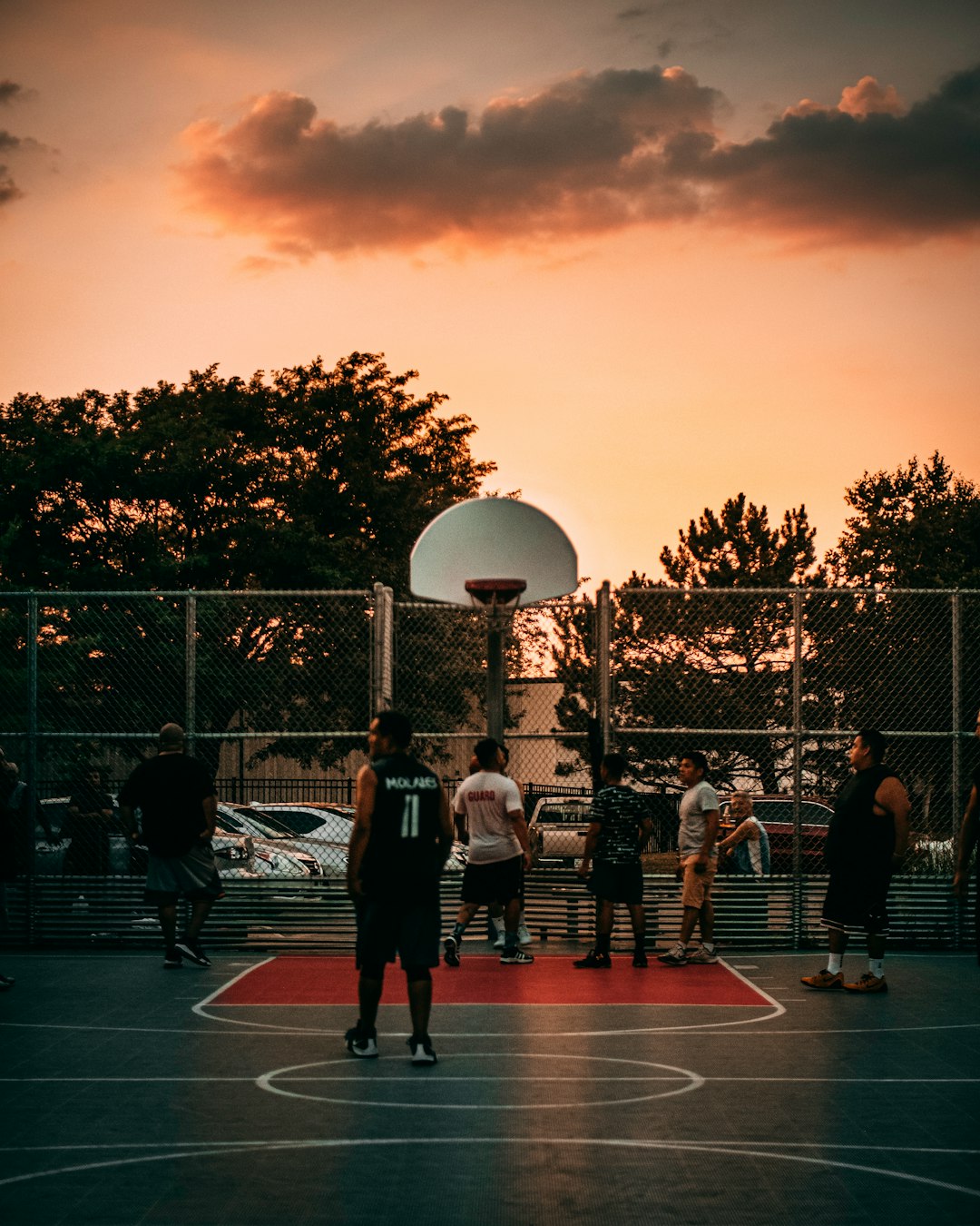 people playing basketball on court during sunset