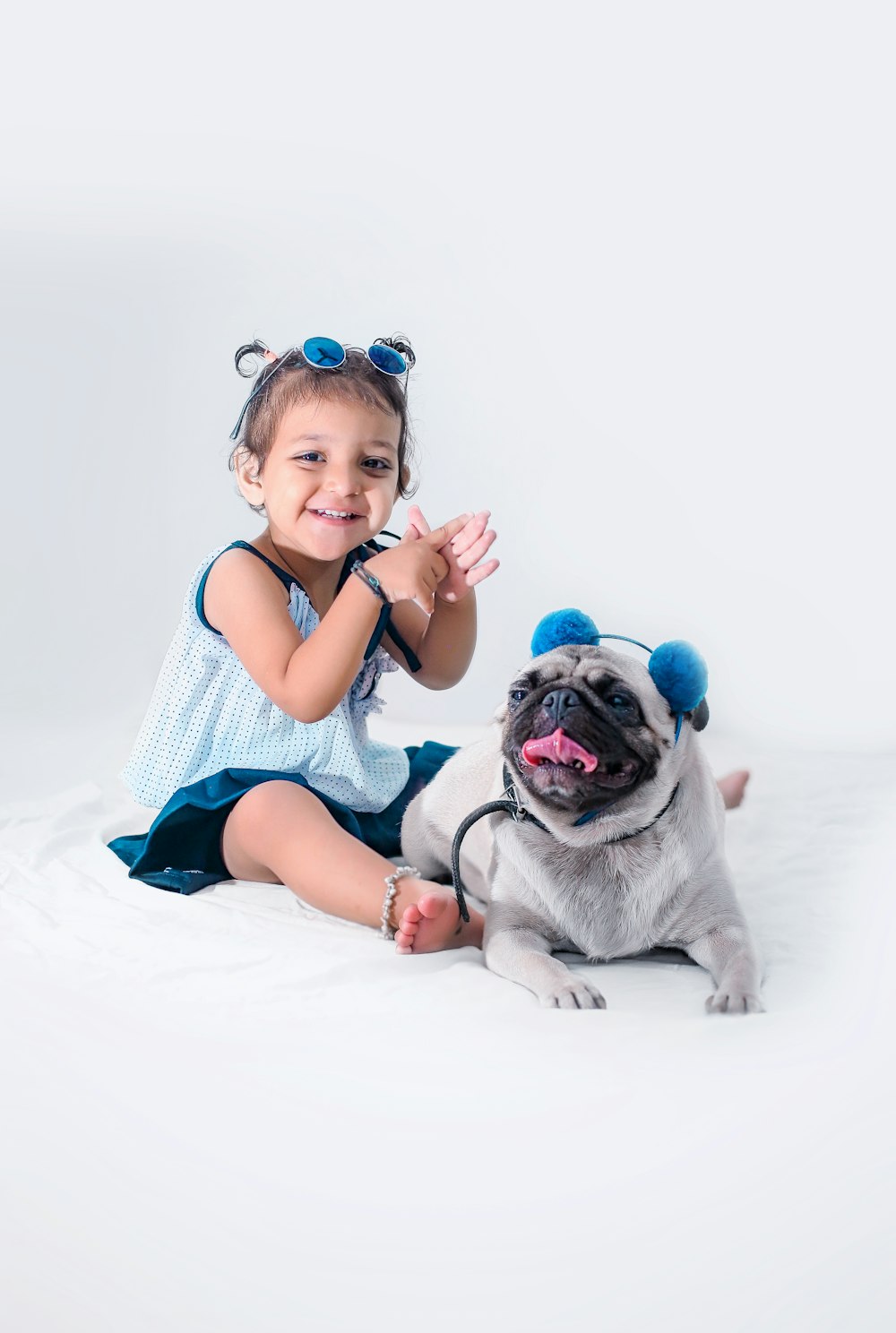 girl in blue and white stripe tank top sitting beside brown pug