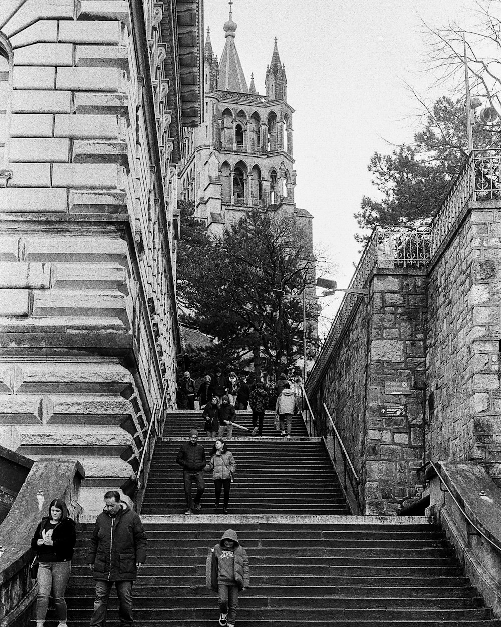 grayscale photo of people walking on stairs near building