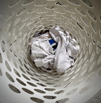 A collapsible laundry basket folded neatly on a bathroom shelf.