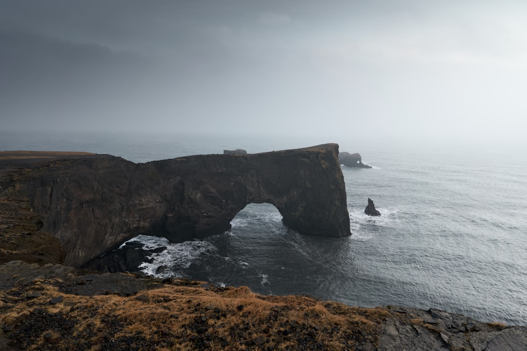 brown rock formation on sea under white clouds during daytime