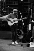A candid shot of a street musician playing guitar in an urban setting.