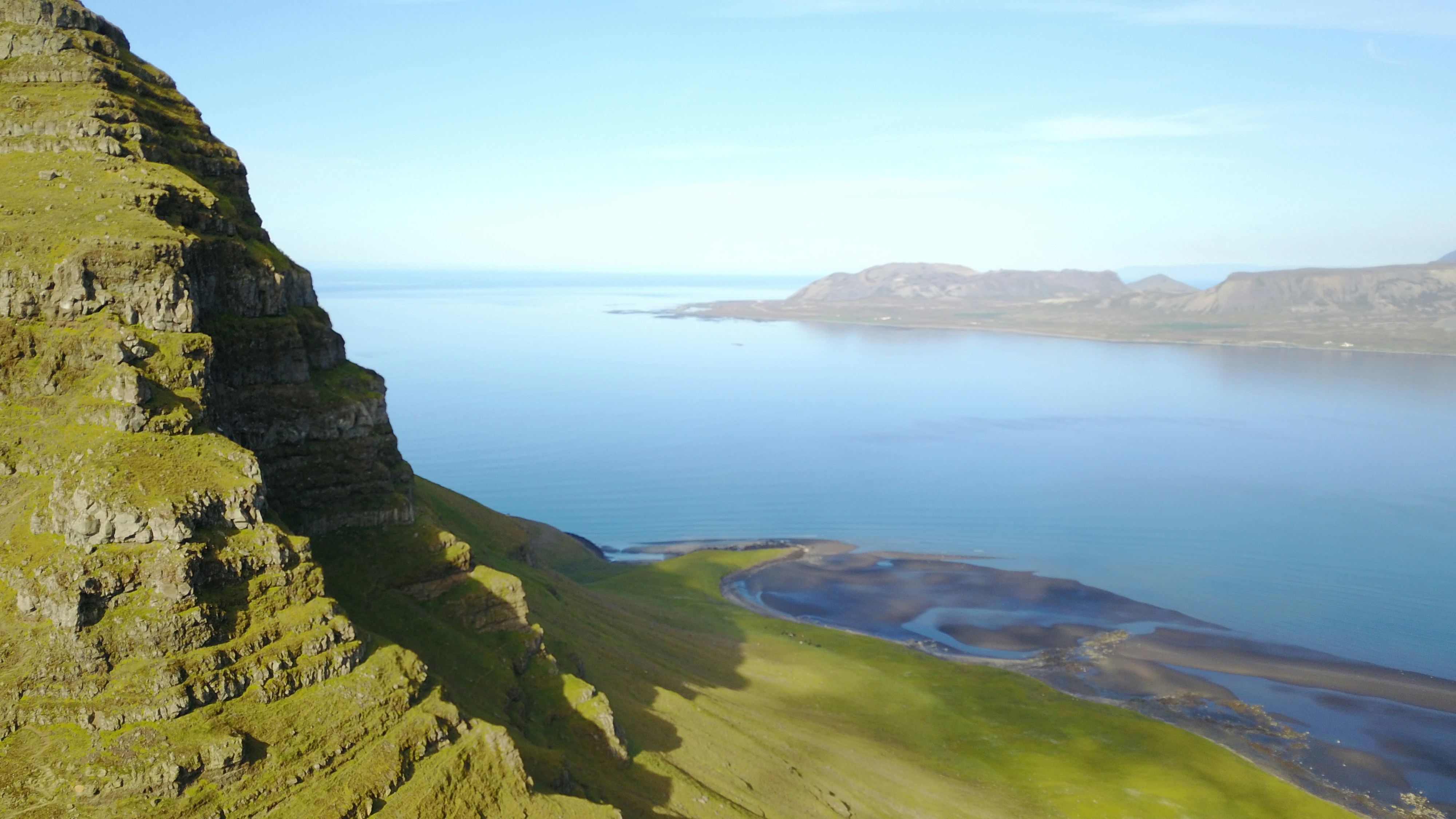 green grass covered mountain beside blue sea under blue sky during daytime, 