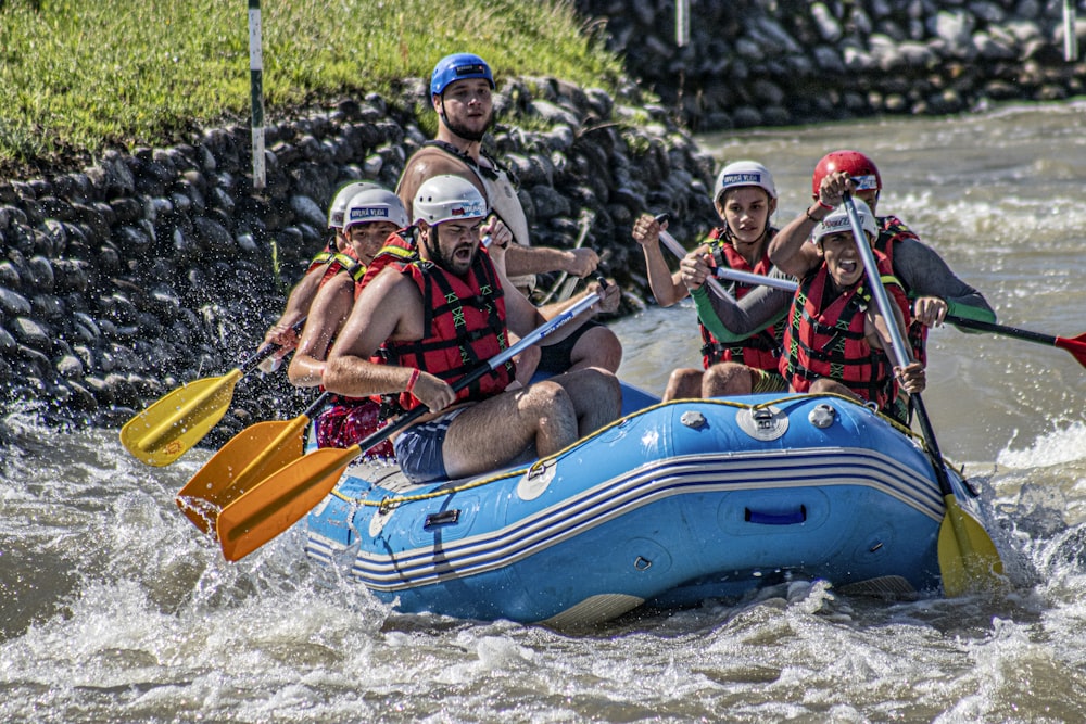 people riding on blue and yellow inflatable boat during daytime