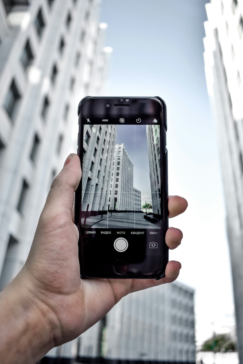 person holding black iphone 4 taking photo of high rise building during daytime