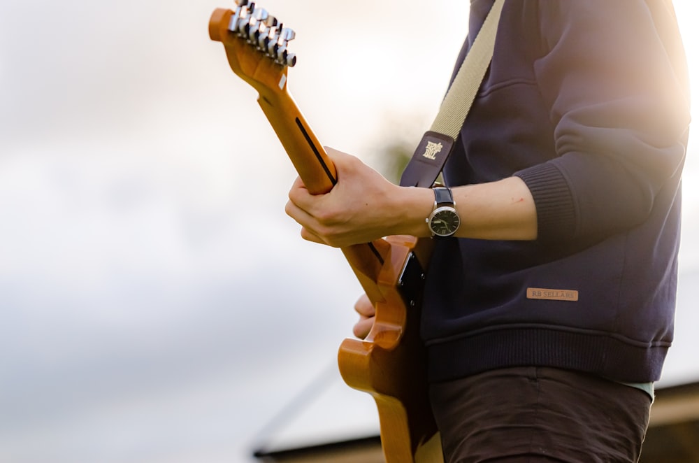 man in white blazer holding brown guitar