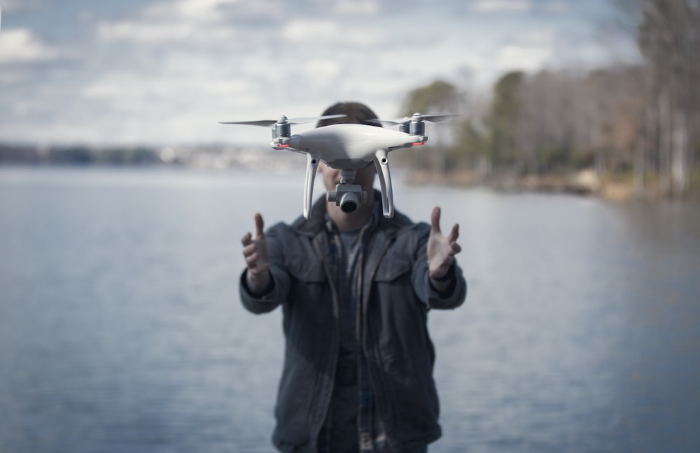 man in black jacket holding white drone