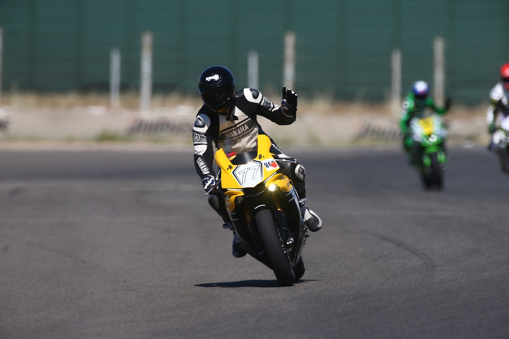man in yellow and black motorcycle suit riding yellow sports bike