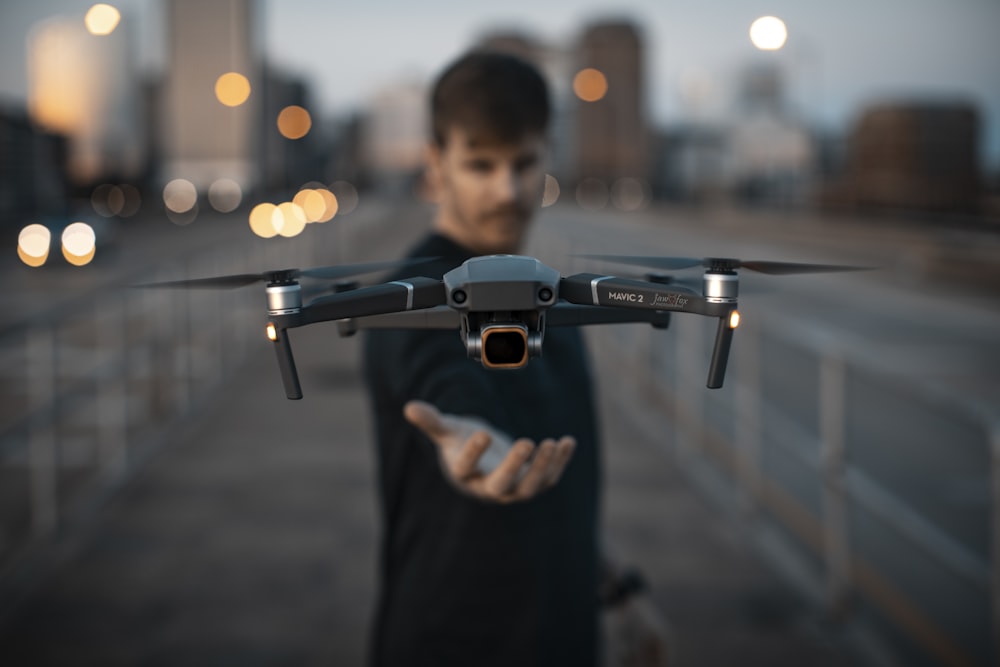 man in black shirt holding black and gray drone