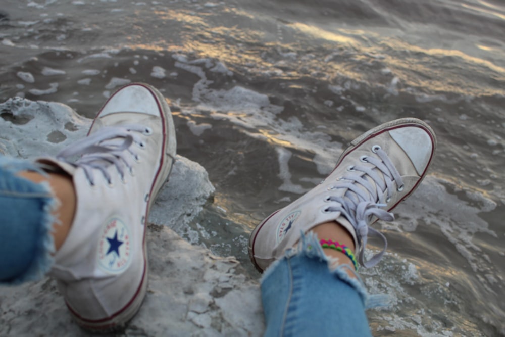 person wearing blue denim jeans and white converse all star high top sneakers