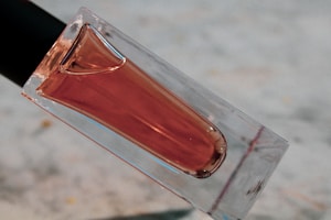 A close-up of a sleek, transparent anal and vaginal wash bottle with soft pink and green monochromatic background, highlighting freshness and hygiene.