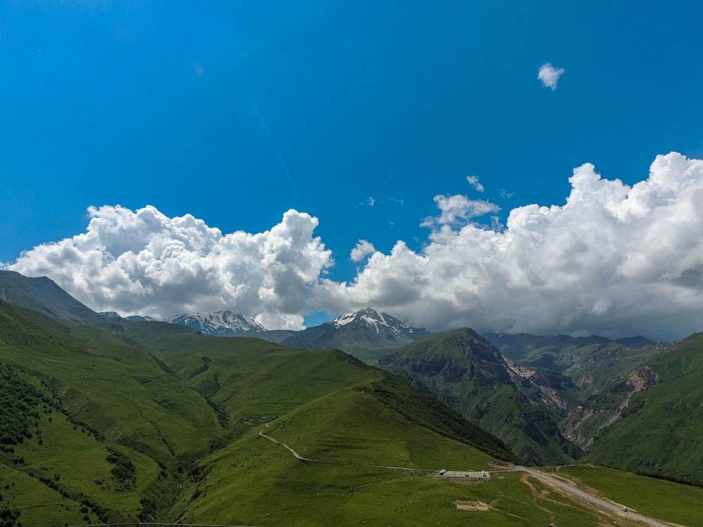 green mountains under blue sky and white clouds during daytime