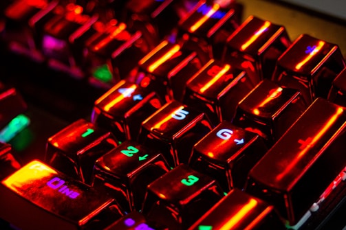 Close-up of a glowing keyboard with red and white neon lights reflecting off sleek black surfaces.