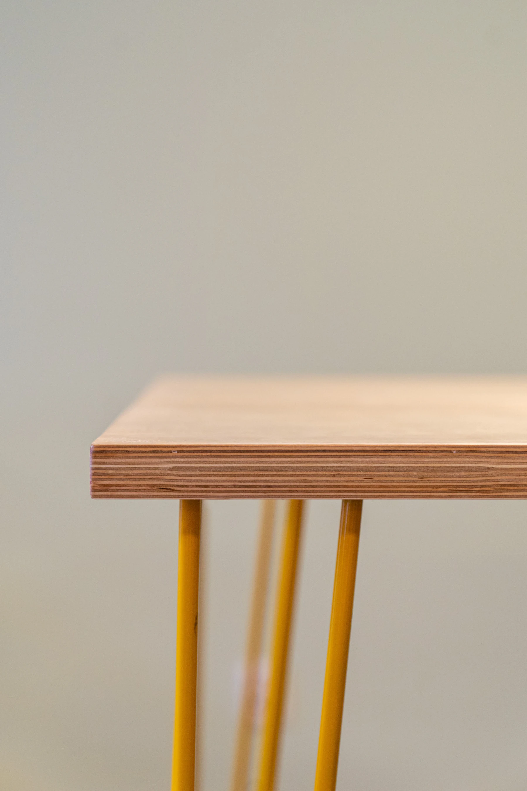 The corner of a plywood table on yellow steel legs