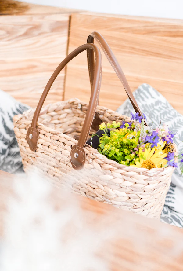 Bolsa de palha com flores sobre uma toalha