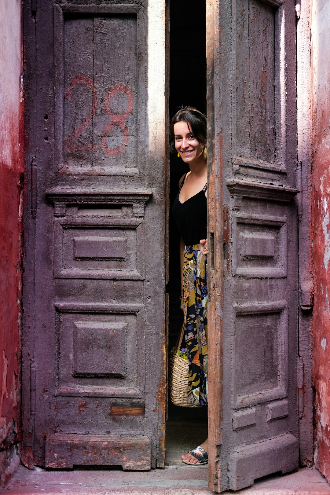woman in blue dress standing beside red wooden door