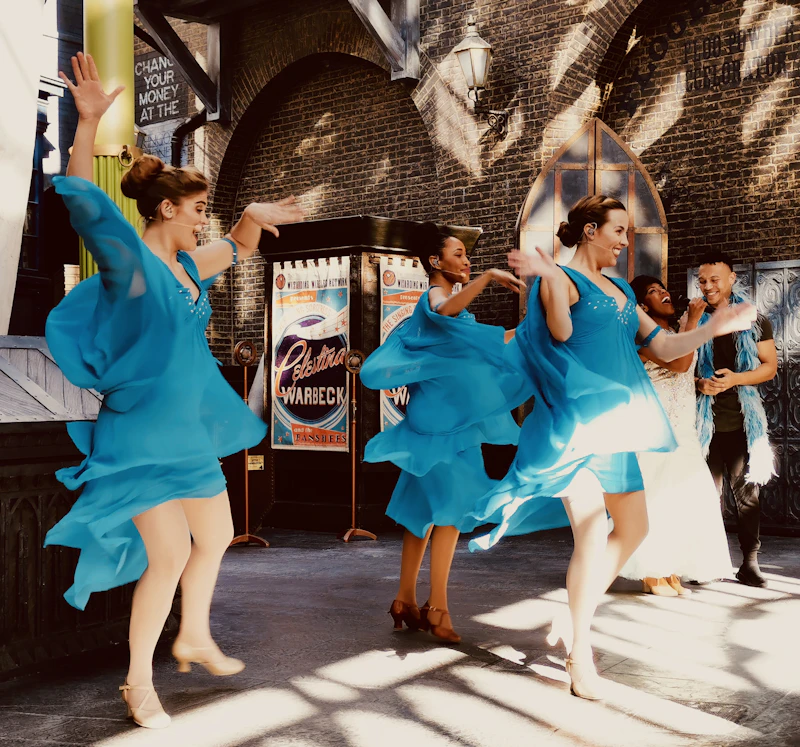 Dancers in flowing blue dresses performing outdoors in daylight