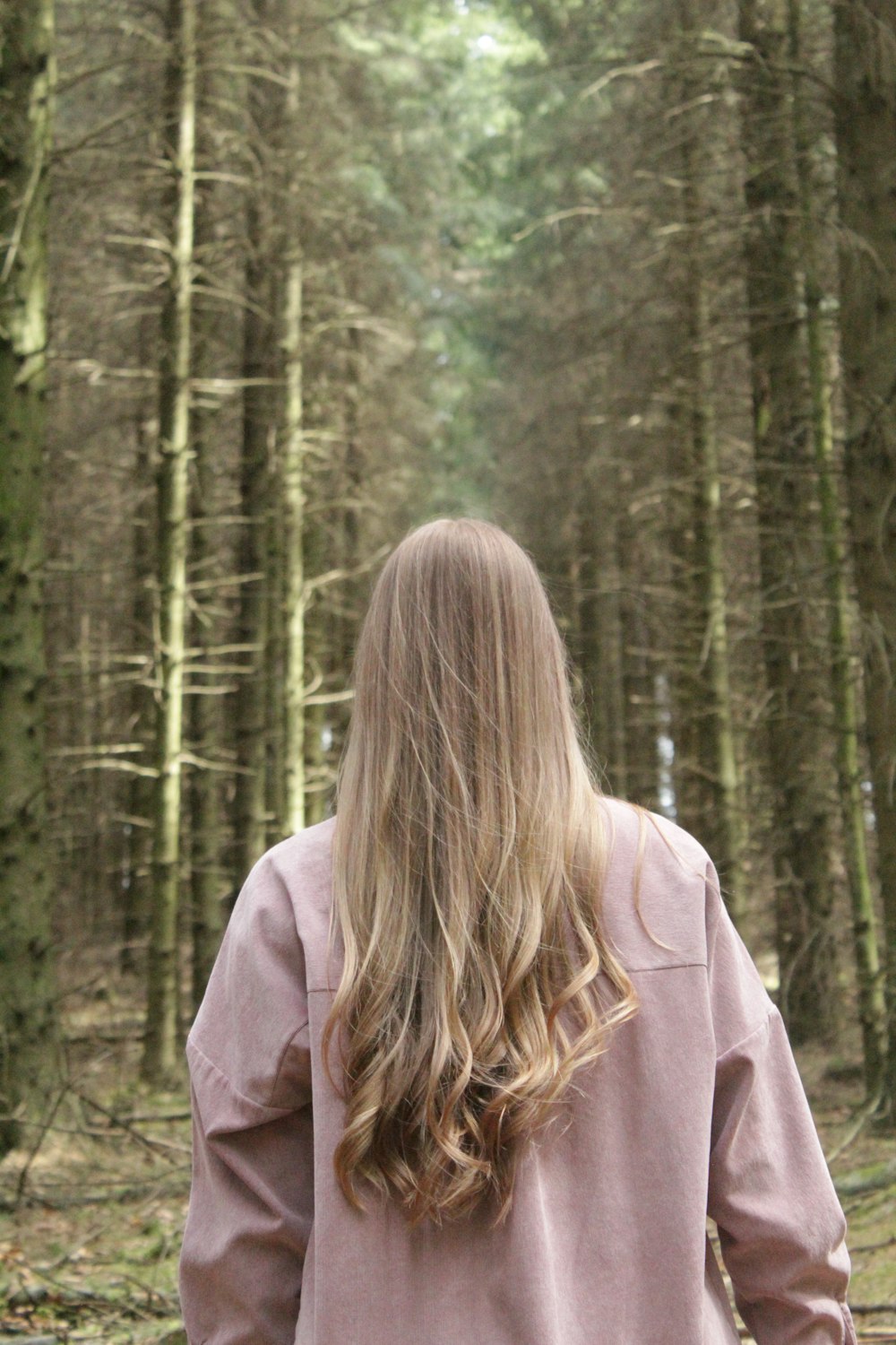 woman in brown hoodie standing in forest during daytime