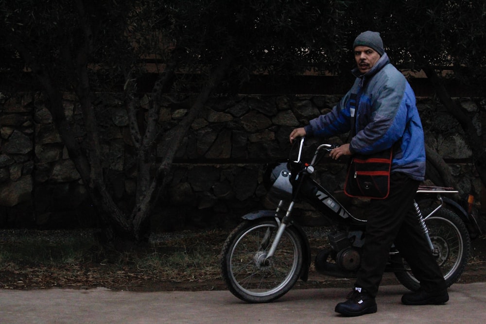 man in blue jacket and black pants riding on red motorcycle