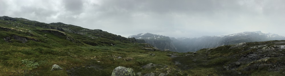 green grass field near mountain under white sky during daytime