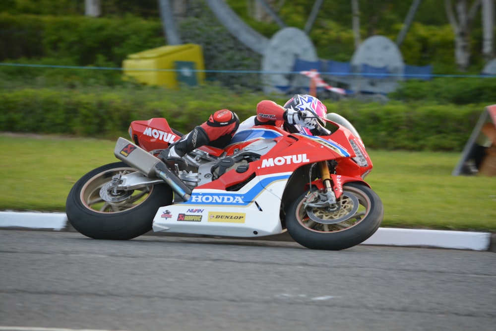 man in red and white racing suit riding on white and blue sports bike