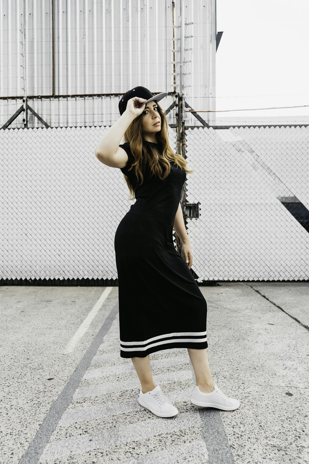 woman in black sleeveless dress standing on gray concrete floor during daytime