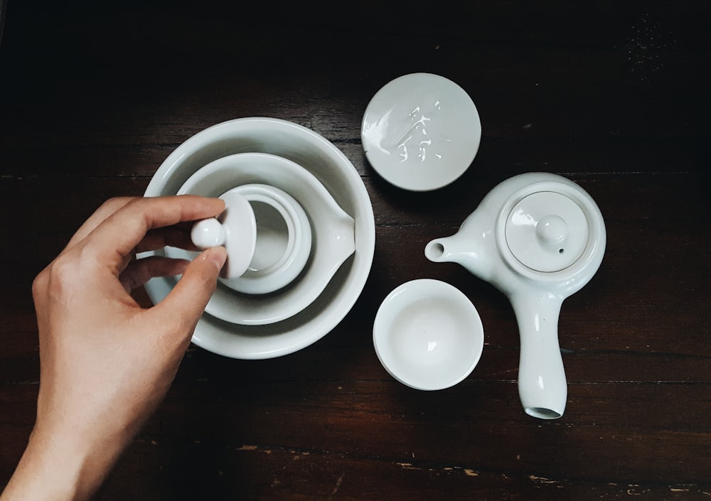 person holding white ceramic teapot