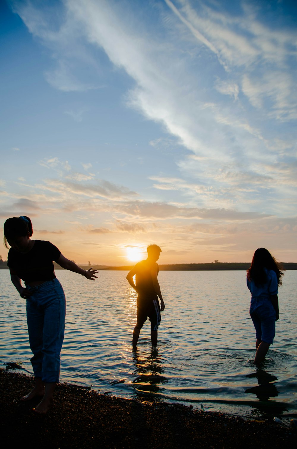 man and woman holding hands while walking on beach during sunset