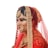 A woman dressed in traditional bridal attire with intricate gold jewelry and a red and gold embroidered veil. Her hair is adorned with floral decorations, and she wears a large nose ring.