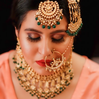 woman in pink dress wearing gold and red beaded necklace