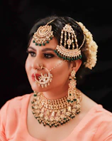 A model wearing a royal black and antique gold necklace set paired with matching earrings at a festive event.