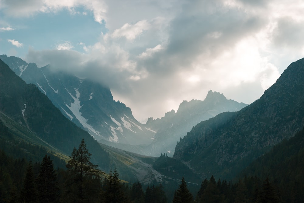 green trees and mountains under white clouds and blue sky during daytime