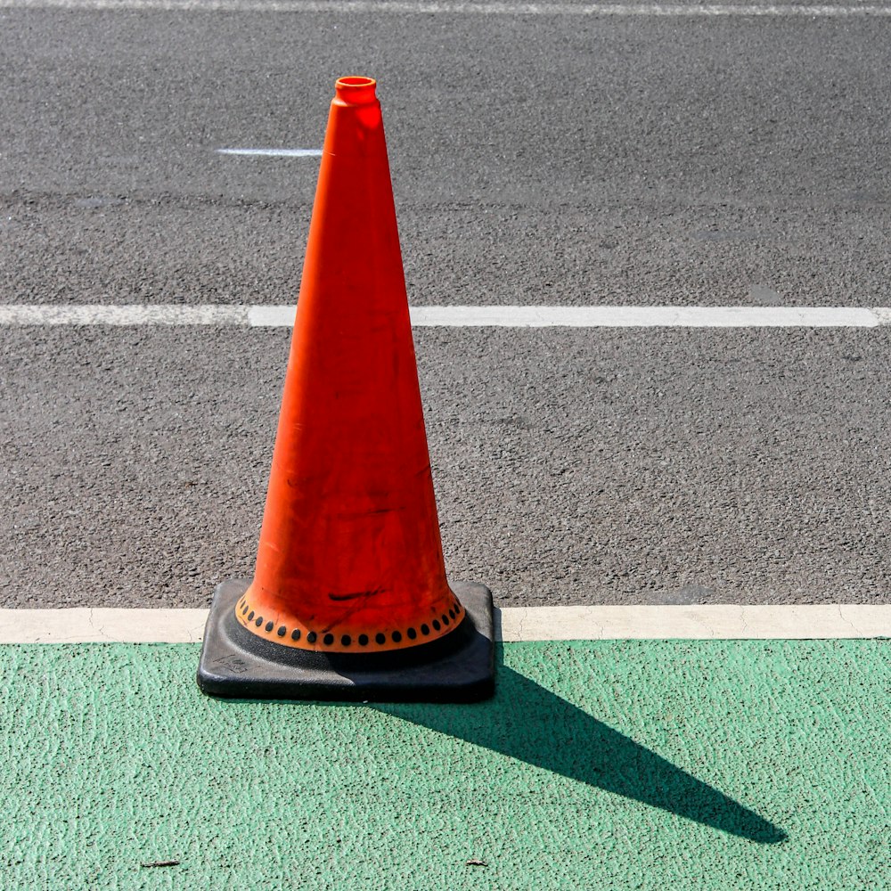 cone de tráfego laranja e preto na estrada de asfalto cinza
