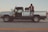 man in white t-shirt and black pants standing beside white crew cab pickup truck