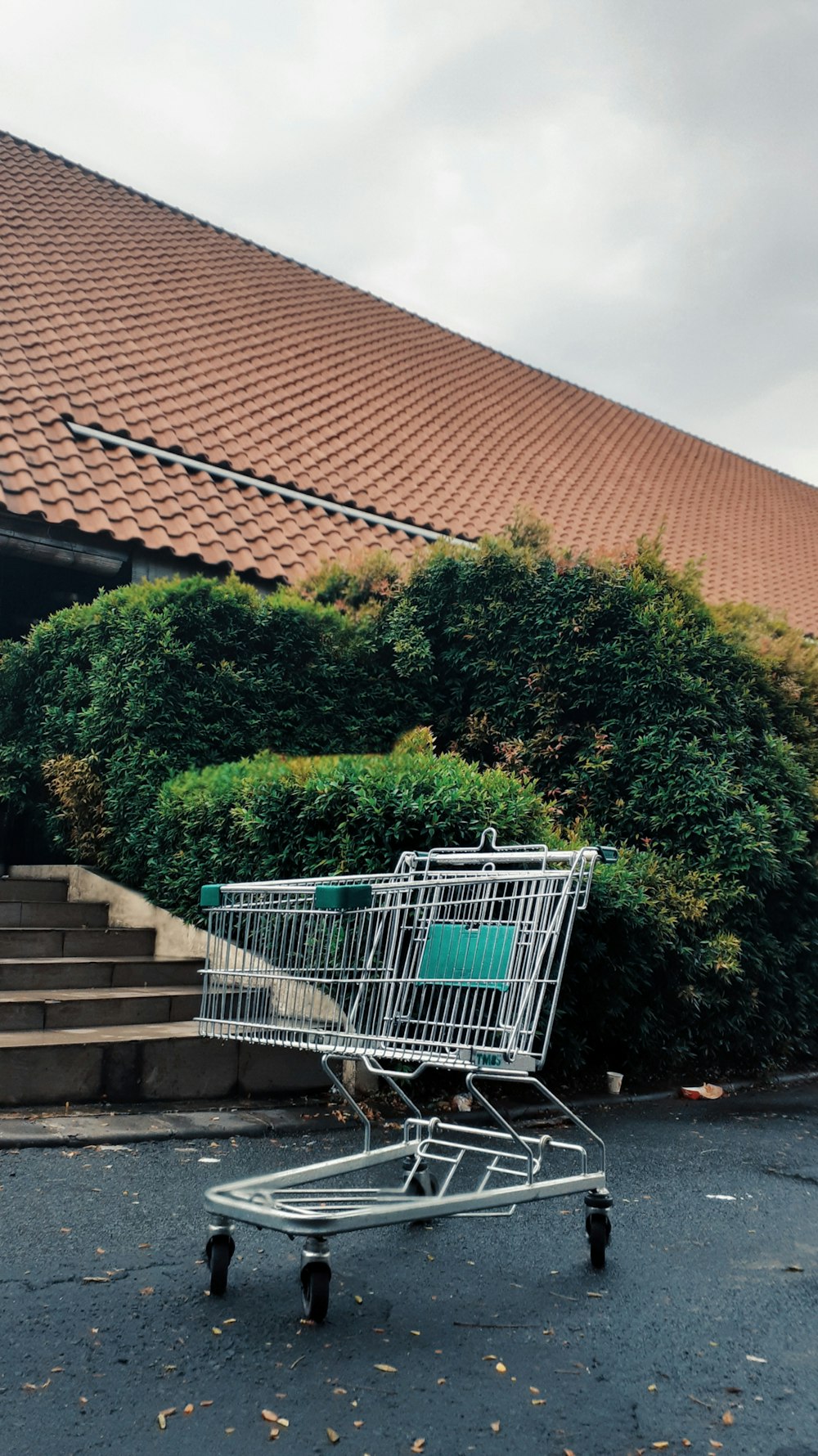 Carro de compras verde en escaleras de hormigón gris