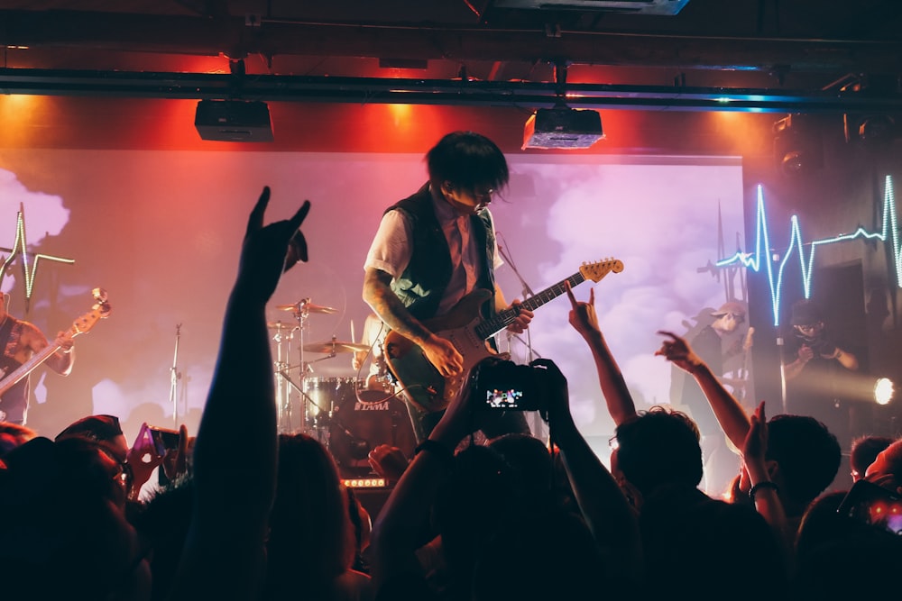 man in black t-shirt playing electric guitar