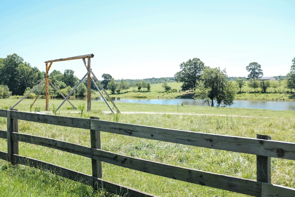 recinzione di legno marrone sul campo di erba verde durante il giorno