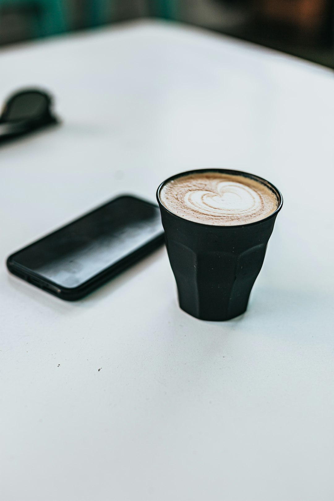 black and white coffee cup beside black iphone 5