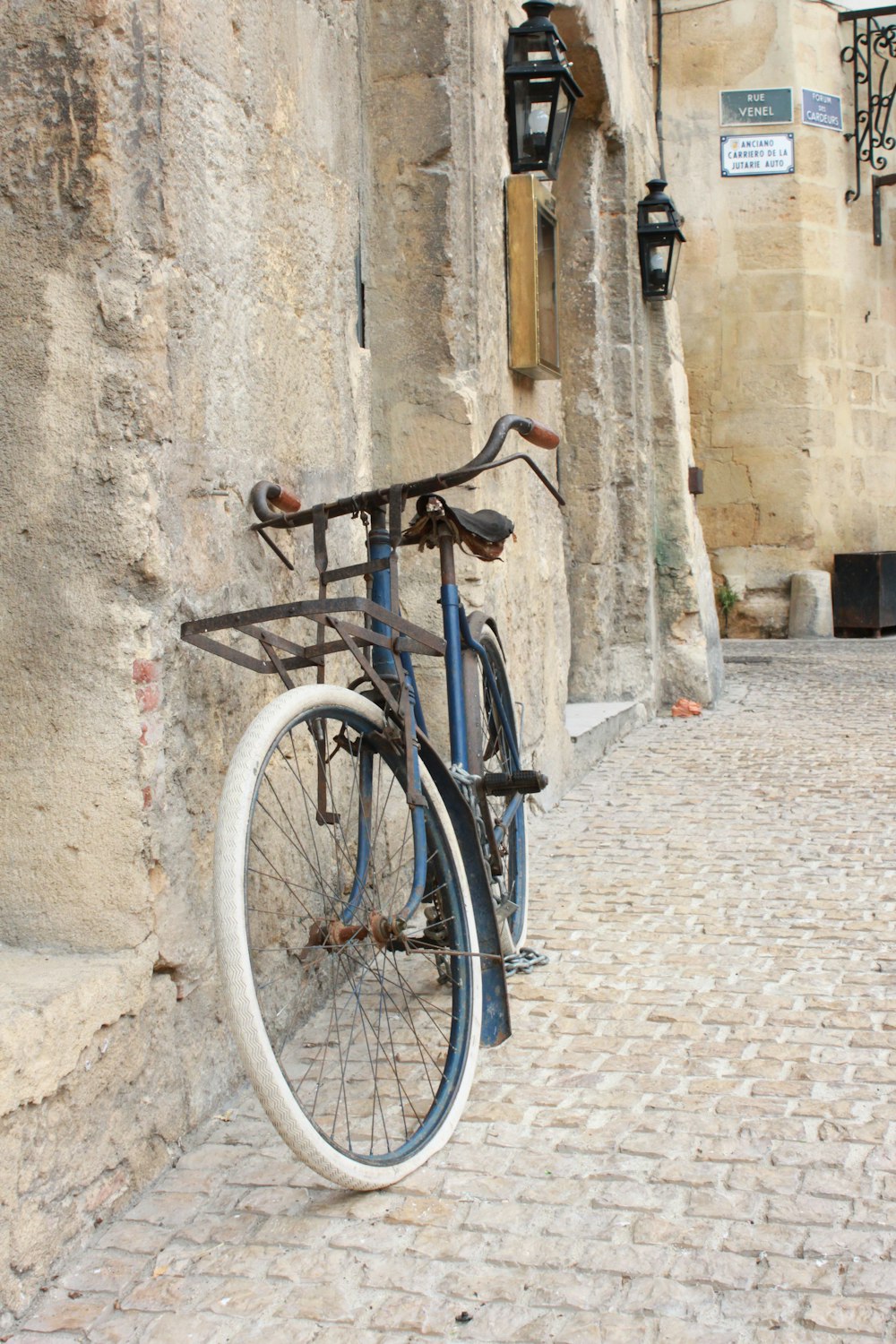 Bicicleta de ciudad azul apoyada en la pared