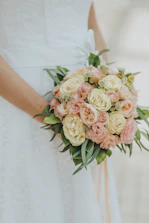 Close-up of a romantic bridal bouquet in soft peach and nude tones with delicate greenery.