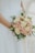 A joyful bride holding a beautifully arranged wedding bouquet from Maskaya.